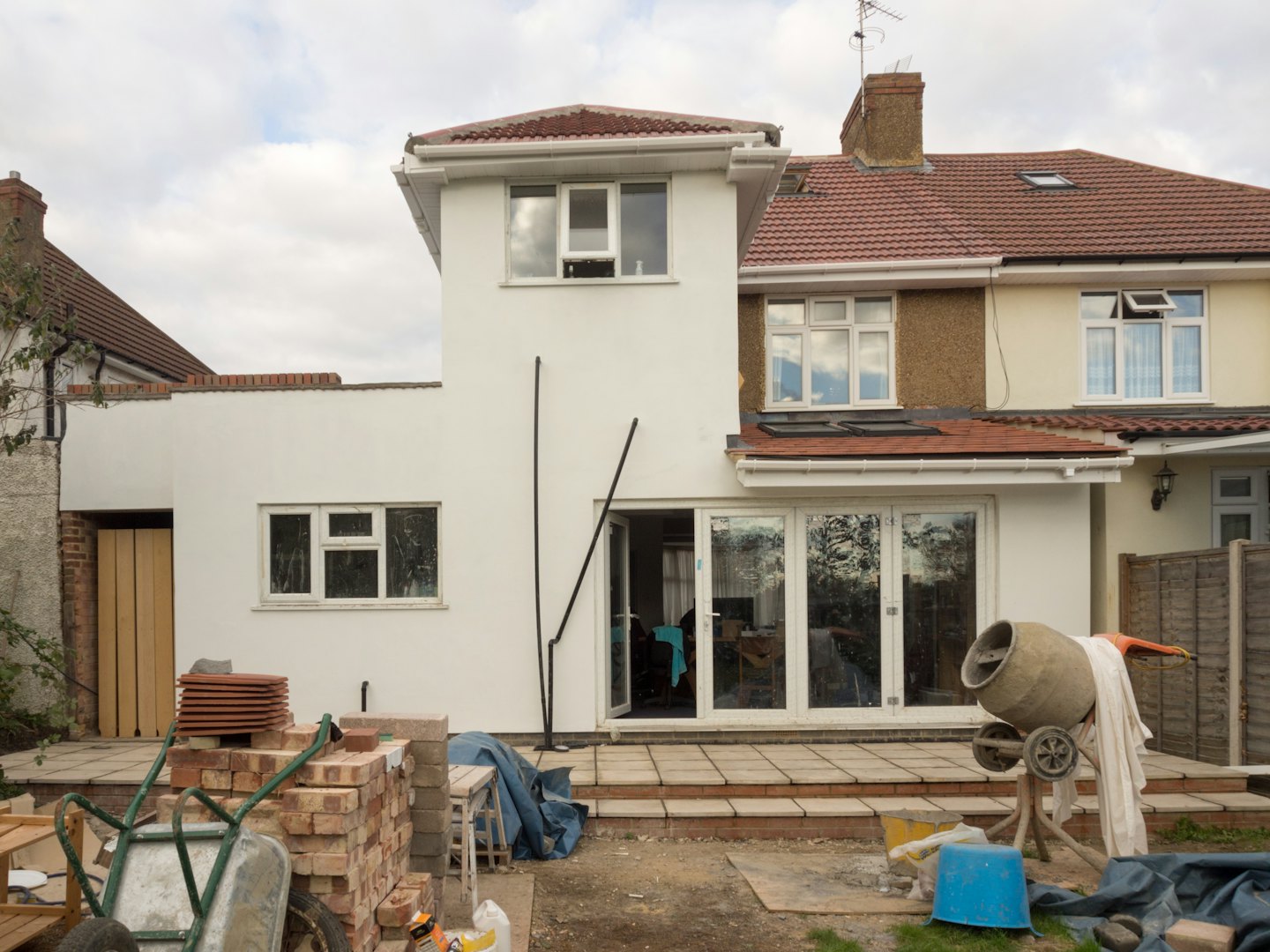 House renovation with new stucco extension and construction materials in yard.