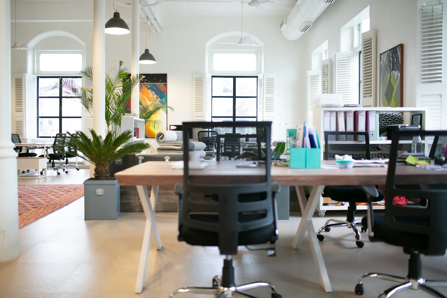 Modern open-plan office with light wood desks and large windows.