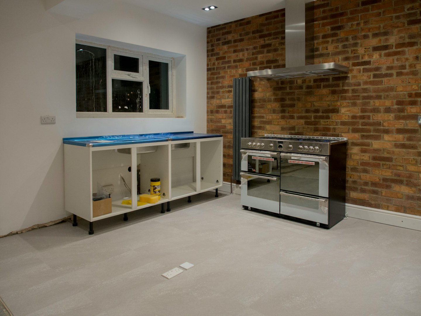 Kitchen renovation with new cabinets and range against brick wall.
