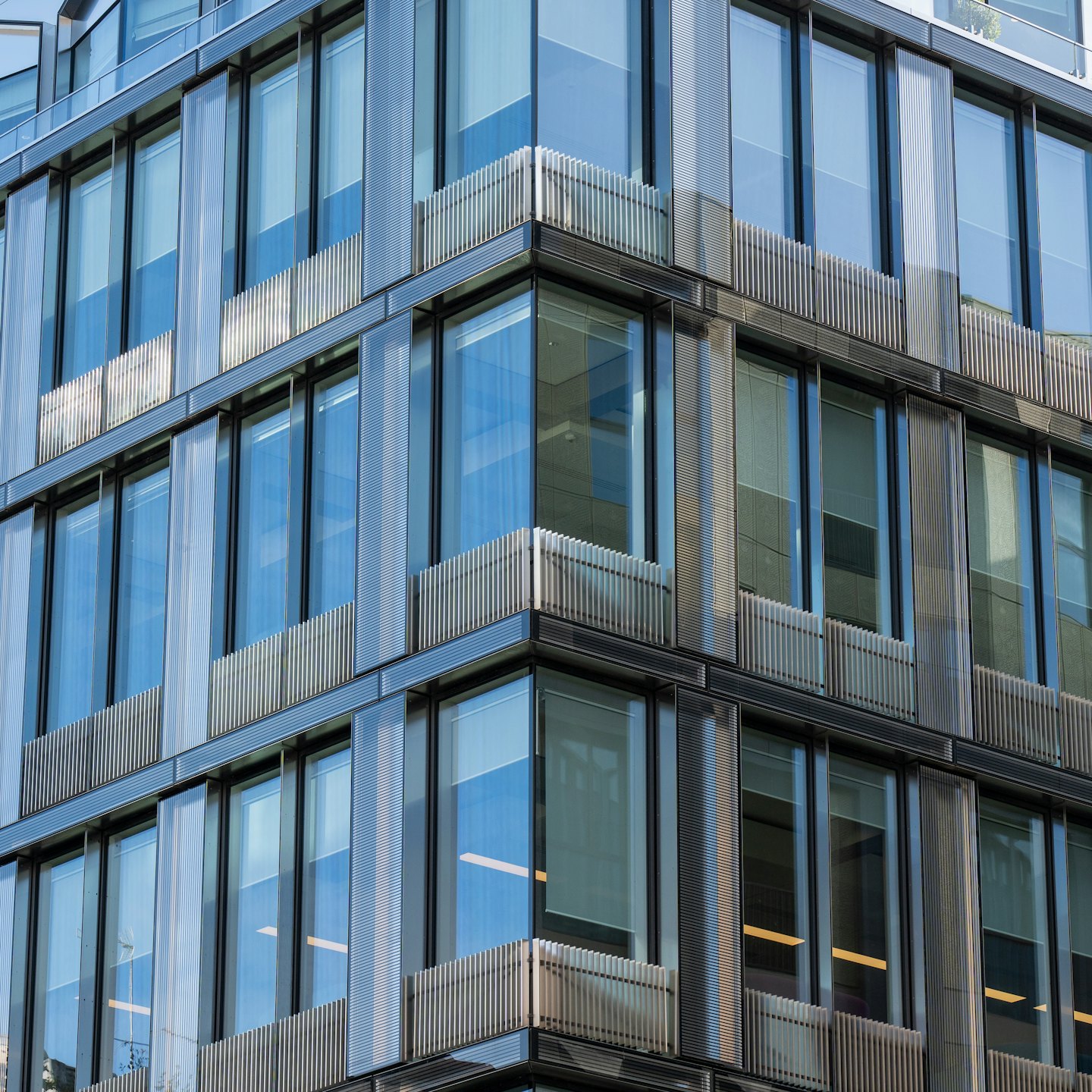 Modern office building with reflective glass windows and metallic fins.